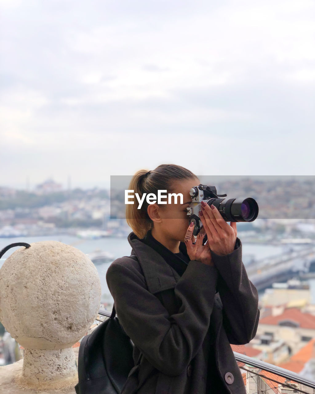 Woman photographing on camera against sky