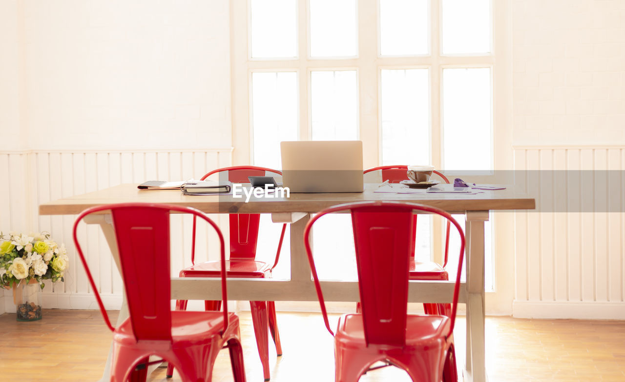 Objects on table by empty chairs in room