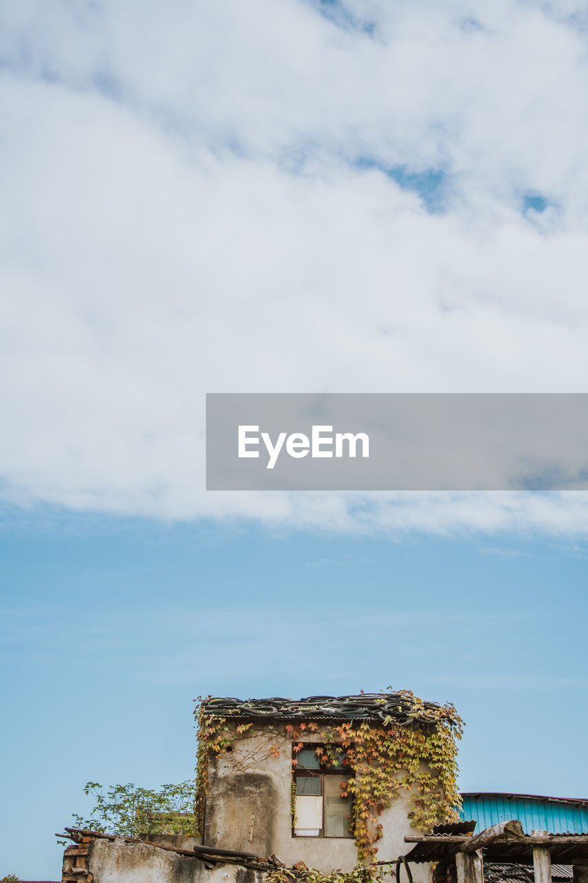 LOW ANGLE VIEW OF ABANDONED BUILDING AGAINST CLOUDY SKY