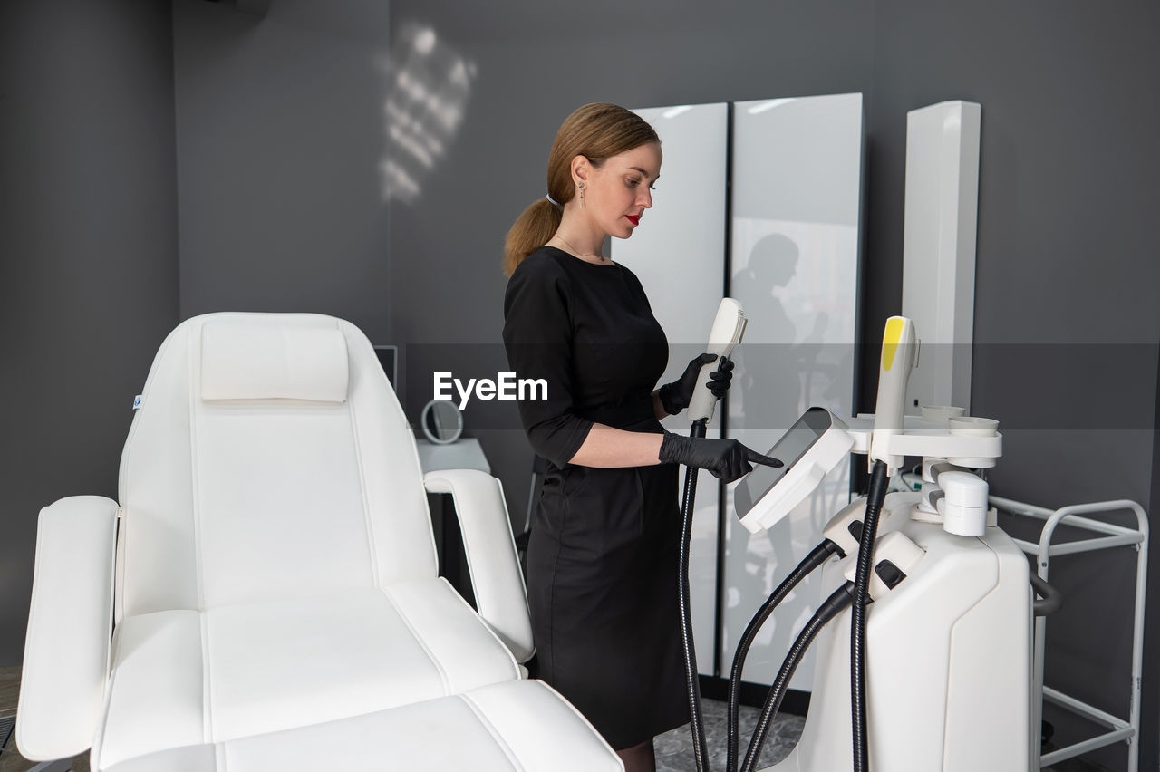 Doctor cosmetologist adjusts the device for photorejuvenation using the touchscreen