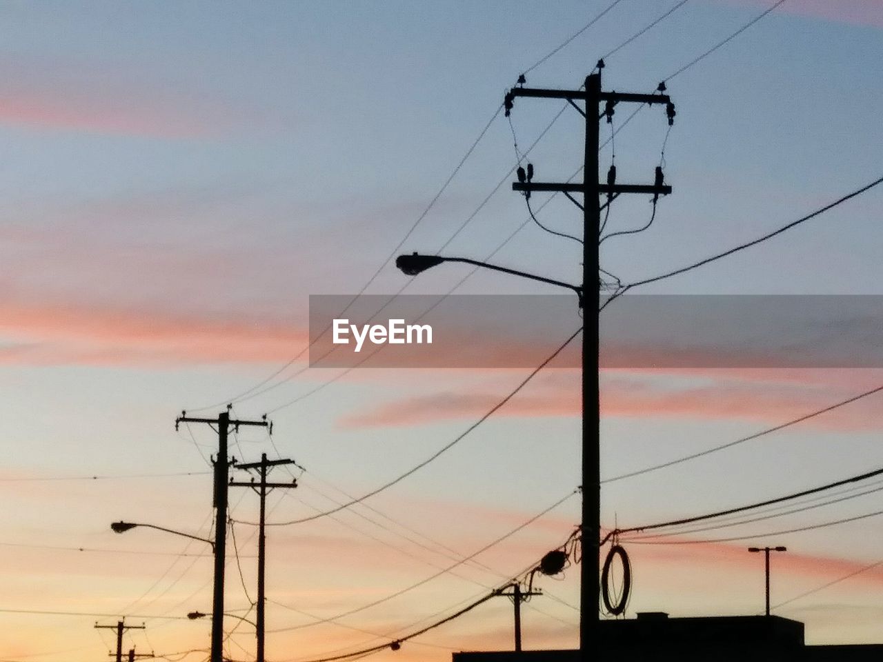 Low angle view of silhouette electricity pylon against sky during sunset