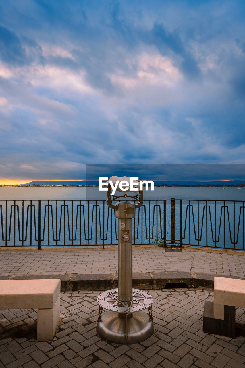 Sunset over the sea with cloudy sky with panoramic binoculars in the foreground