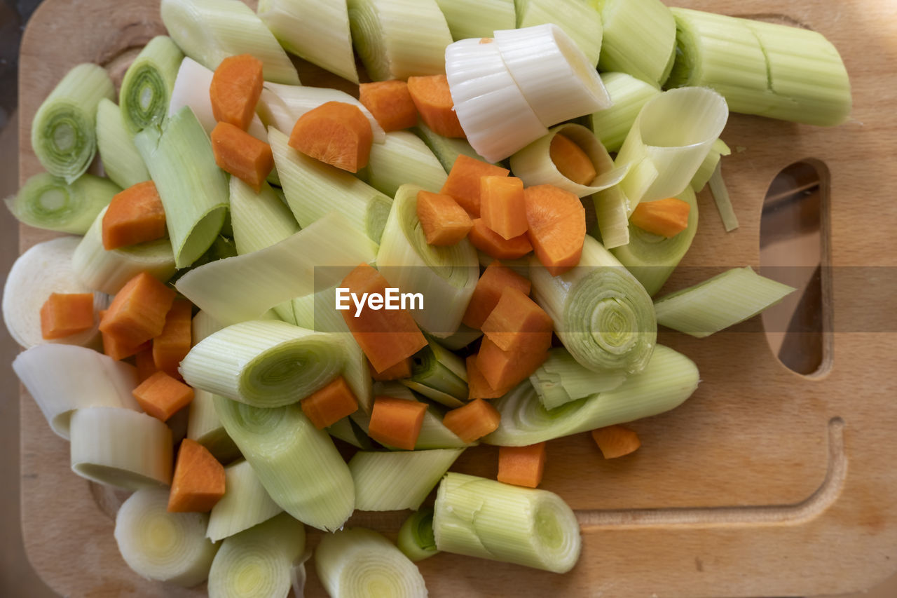 Ready for healthy dinner cooking sliced organic leek and carrot pieces on the wooden cutting board,