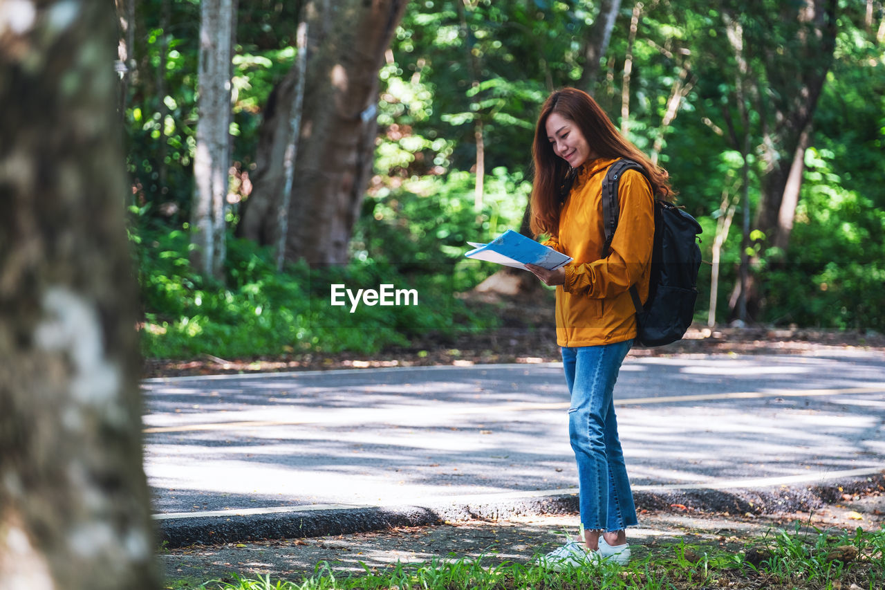 portrait of young woman walking on footpath in forest