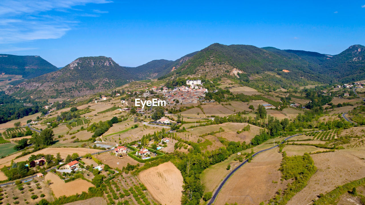 HIGH ANGLE VIEW OF TOWNSCAPE BY MOUNTAINS AGAINST SKY