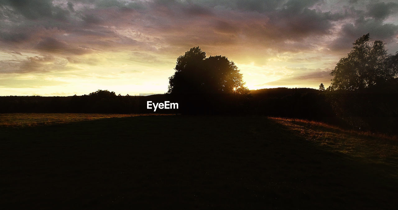 SCENIC VIEW OF SILHOUETTE FIELD AGAINST SKY DURING SUNSET