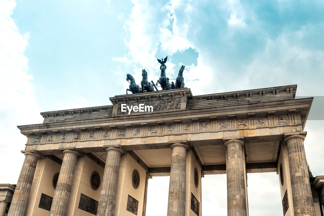 Low angle view of brandenburg gate against cloudy sky