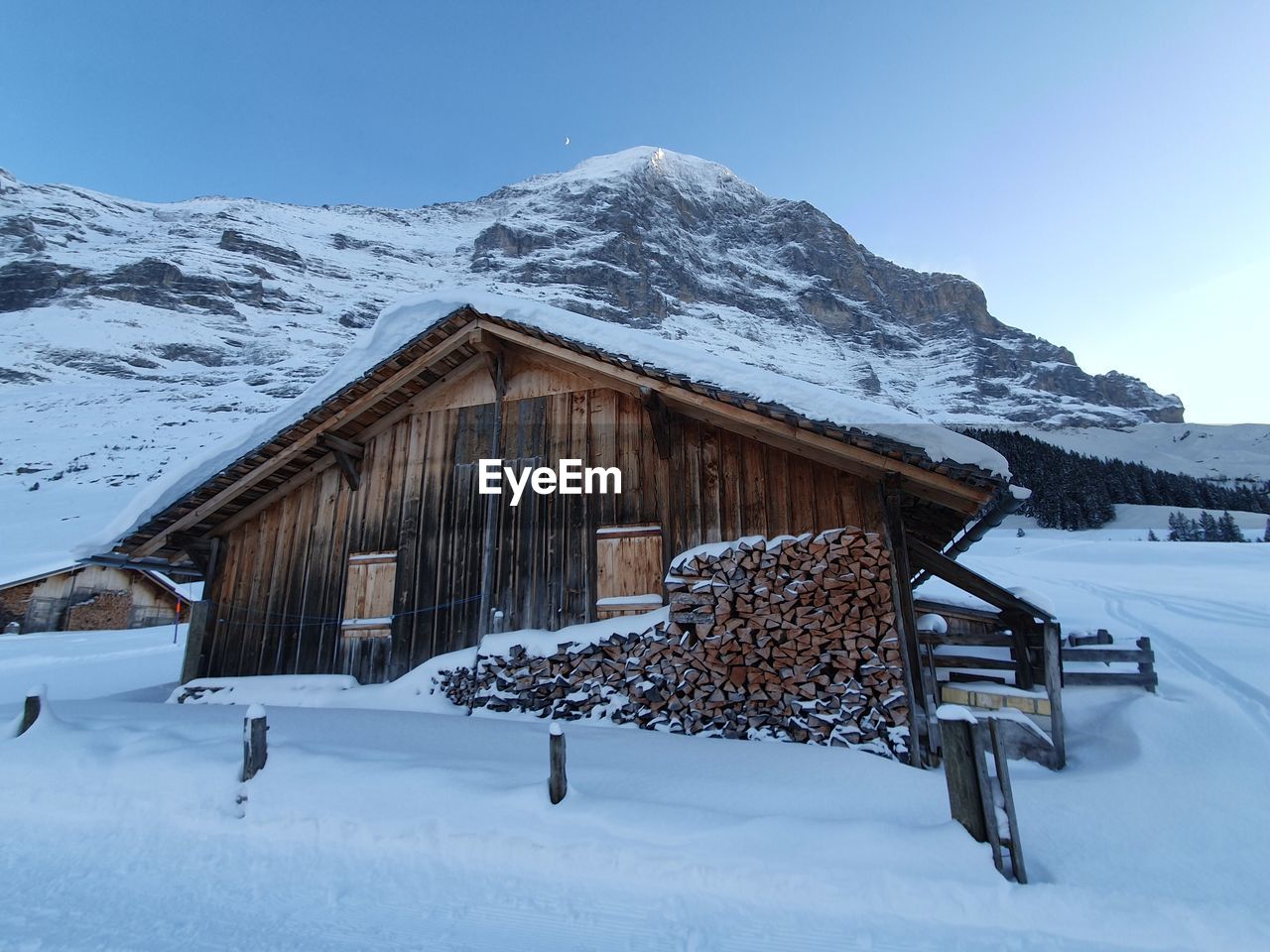 Snow covered landscape and swiss  mountains with a house infront