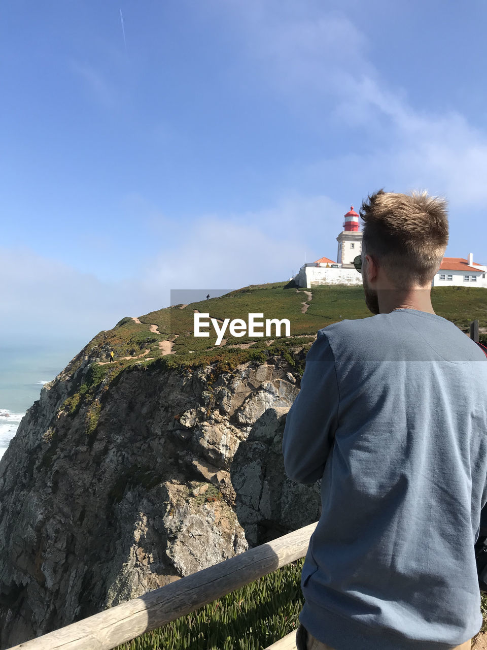 REAR VIEW OF MAN LOOKING AT SEA