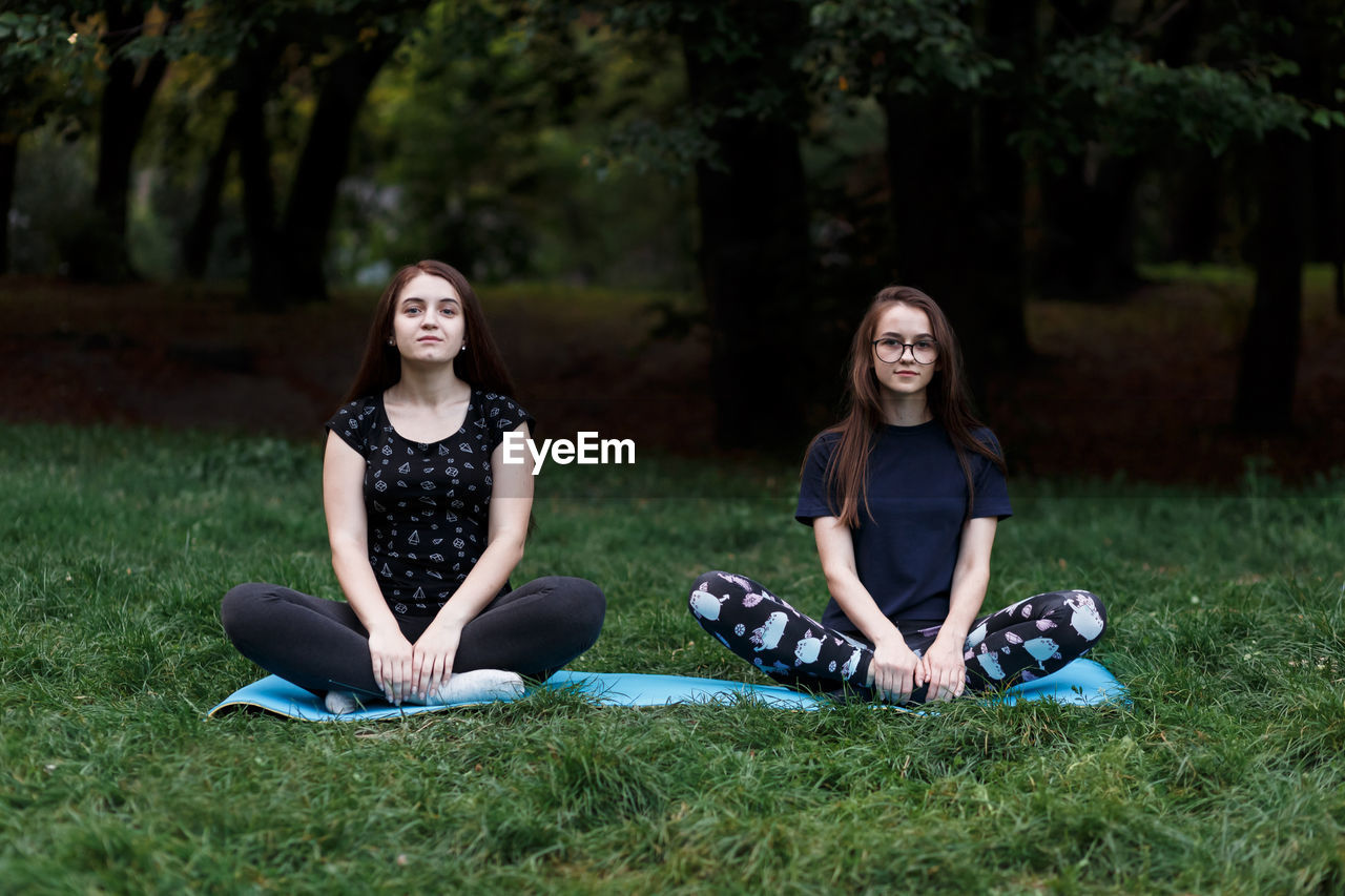 The relaxed girls is doing yoga in the park on carpet