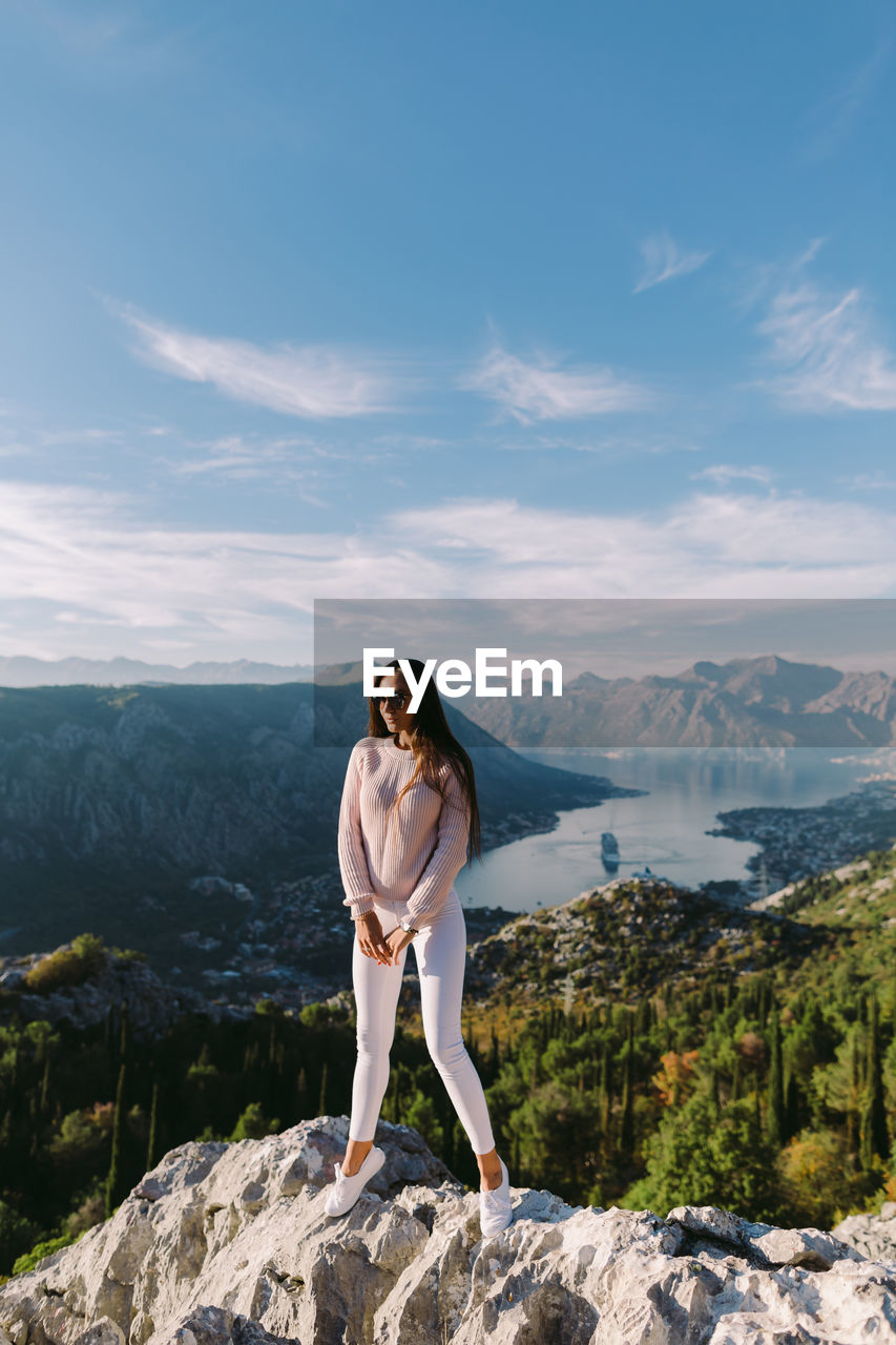 Full length of woman standing on mountain against sky