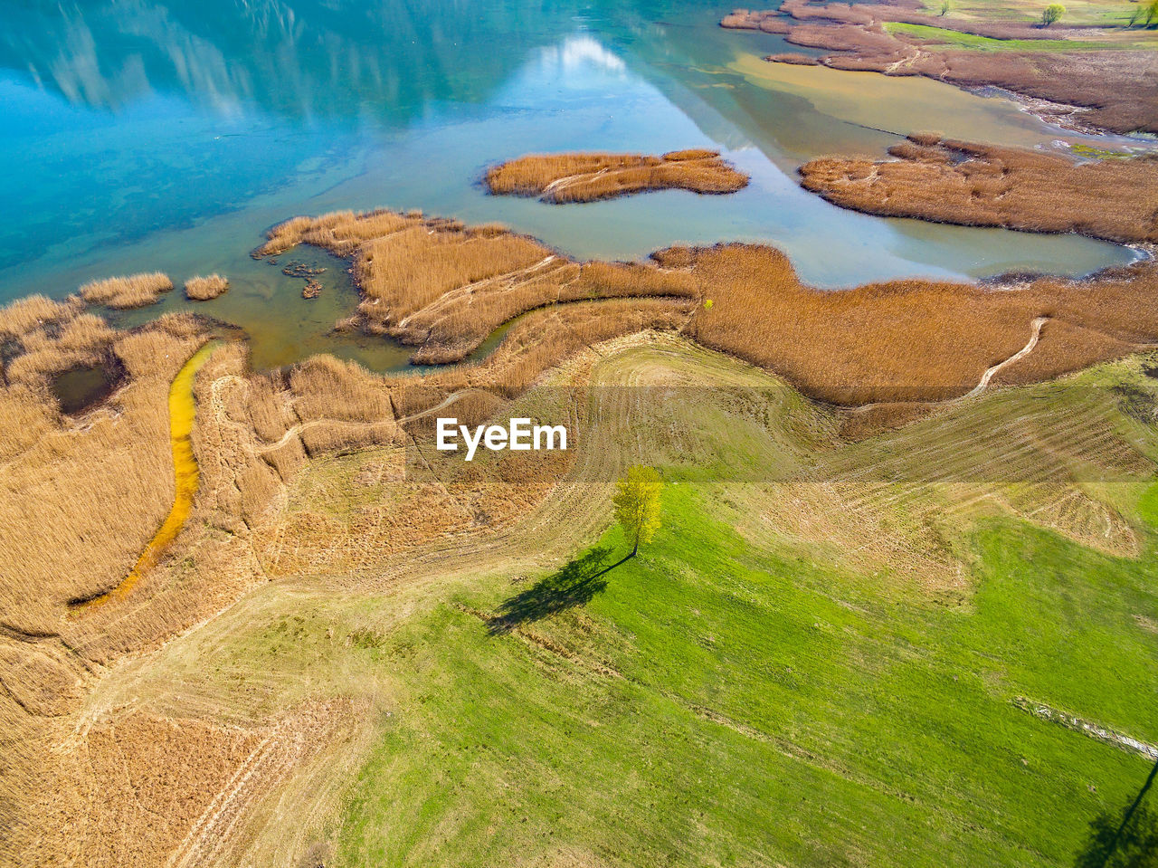 HIGH ANGLE VIEW OF LAND AMIDST WATER ON FIELD