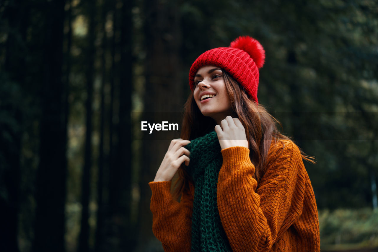 Young woman looking away in forest during winter