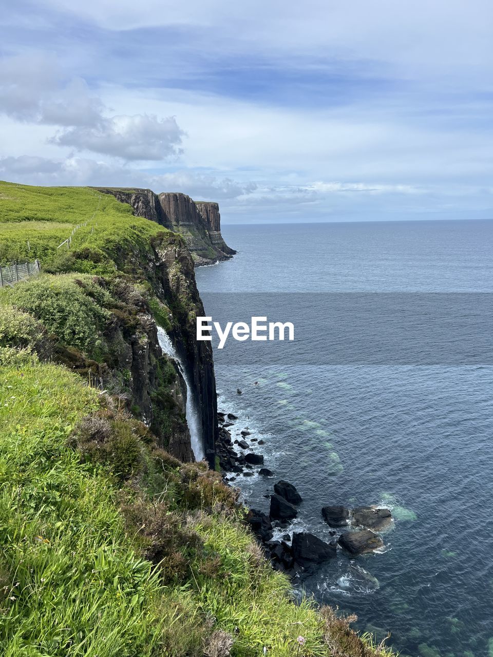 water, nature, cliff, beauty in nature, plant, terrain, scenics - nature, day, no people, motion, mountain, land, sea, outdoors, high angle view, architecture, sky, tree, cloud, mountain range, environment, tranquility, coast, panoramic, green, non-urban scene, waterfall, built structure, tranquil scene