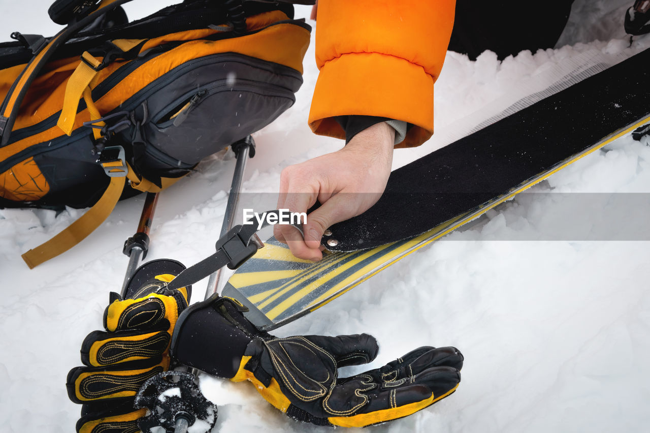 Close-up of a man's hand, adjusting the skis against the background of snow and things, putting on