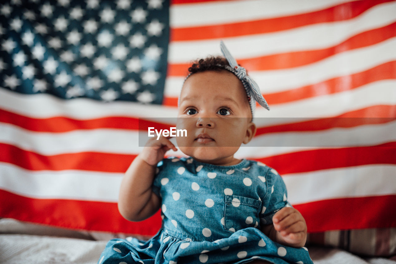 Portrait of cute girl sitting on red flag