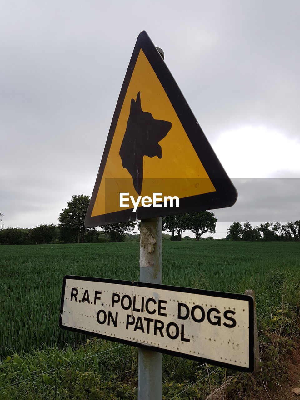 SIGN BOARD ON GRASSY FIELD AGAINST SKY