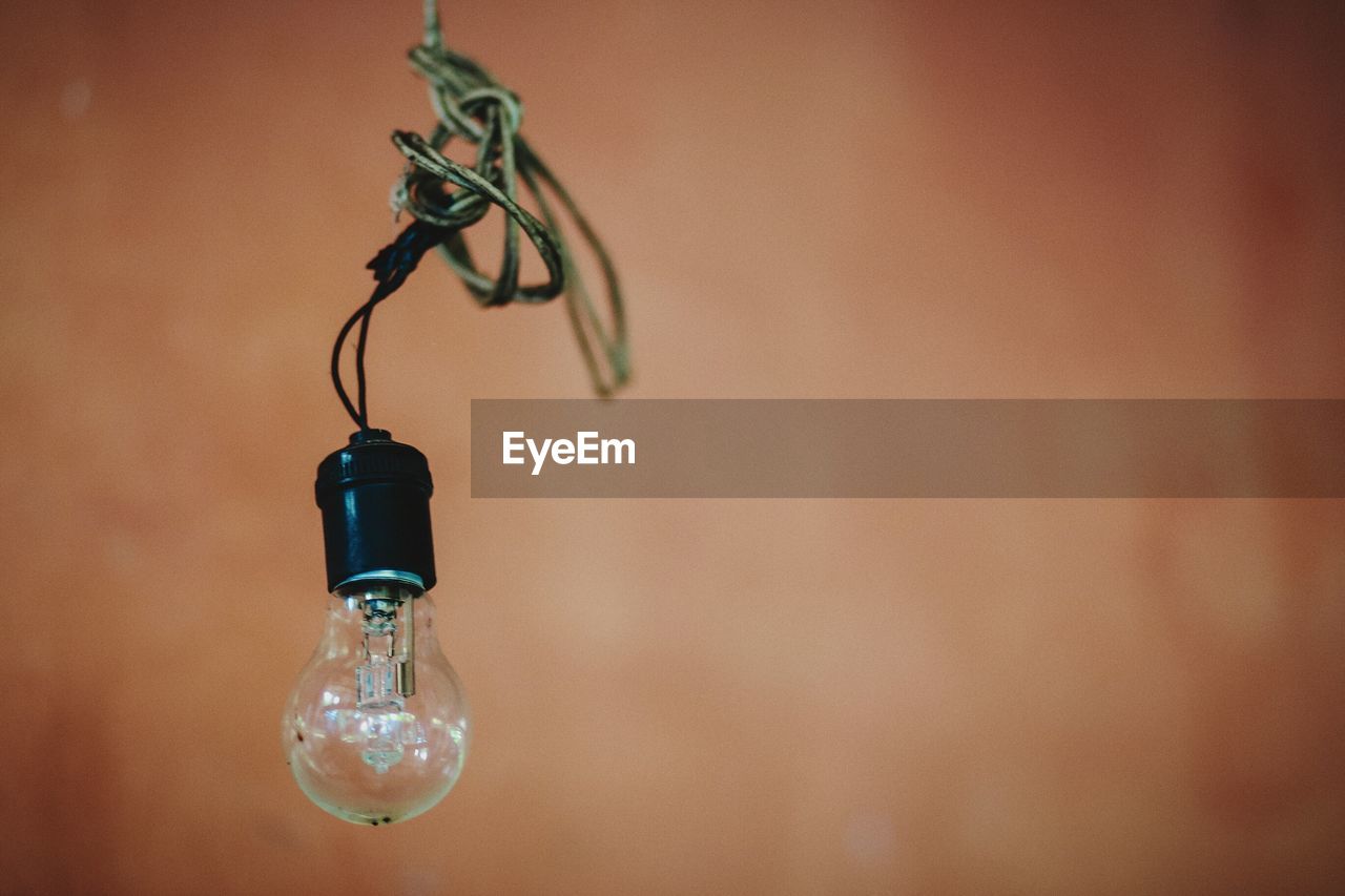 CLOSE-UP OF LIGHT BULB HANGING FROM WALL