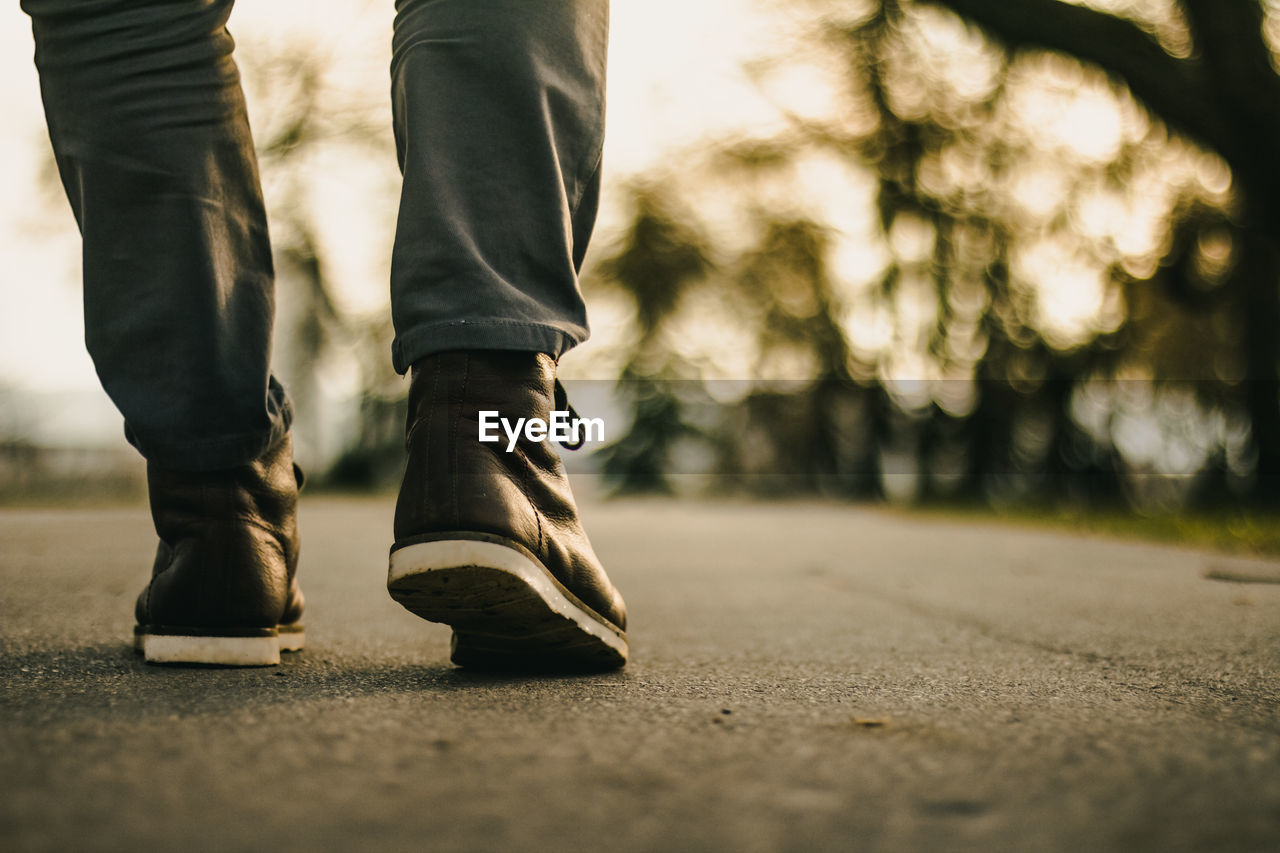 Low section of man walking on road