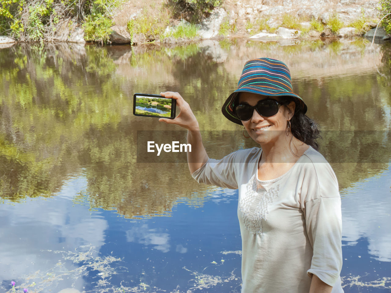 Portrait of woman using mobile phone while standing by lake