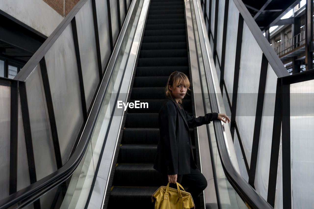 Woman standing on escalator