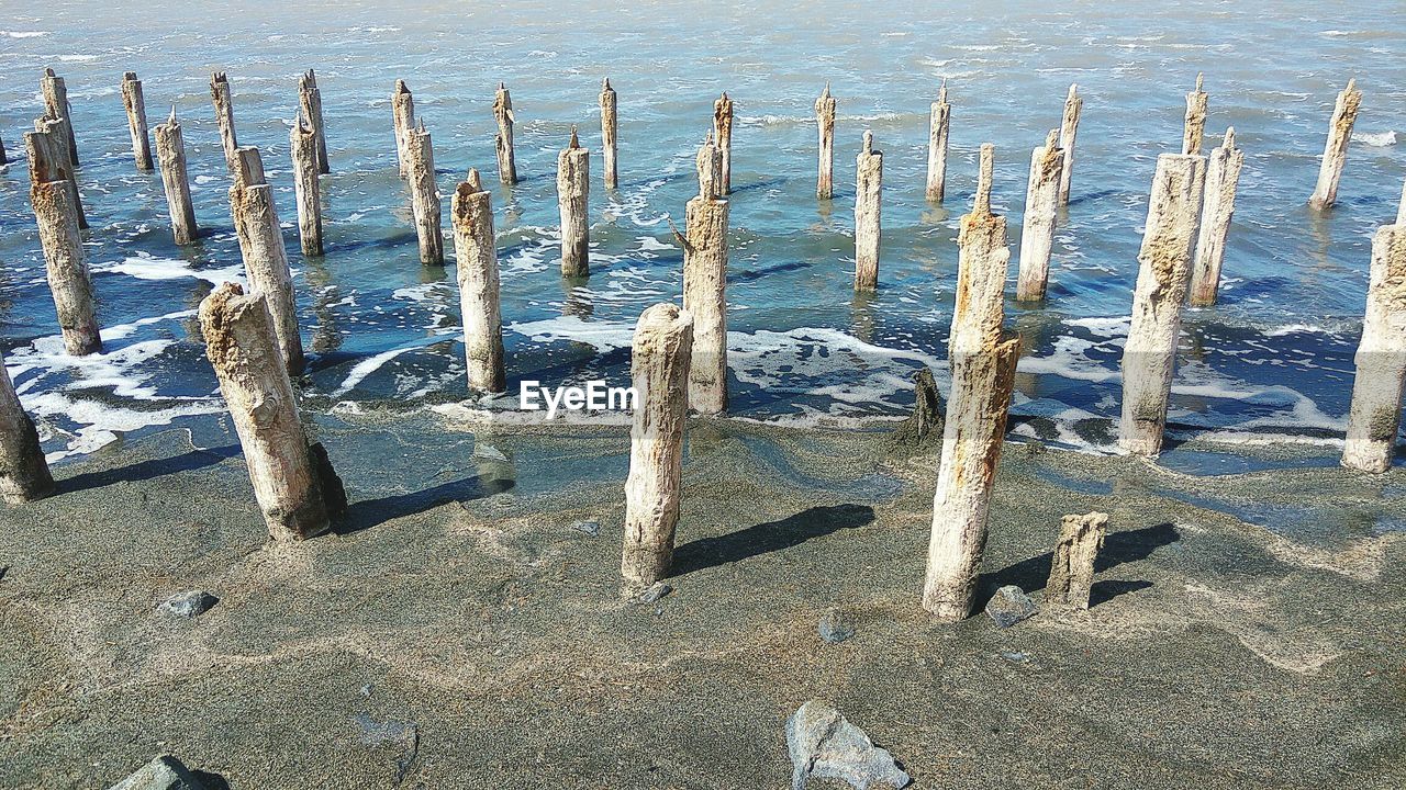 High angle view of wooden posts on beach during winter