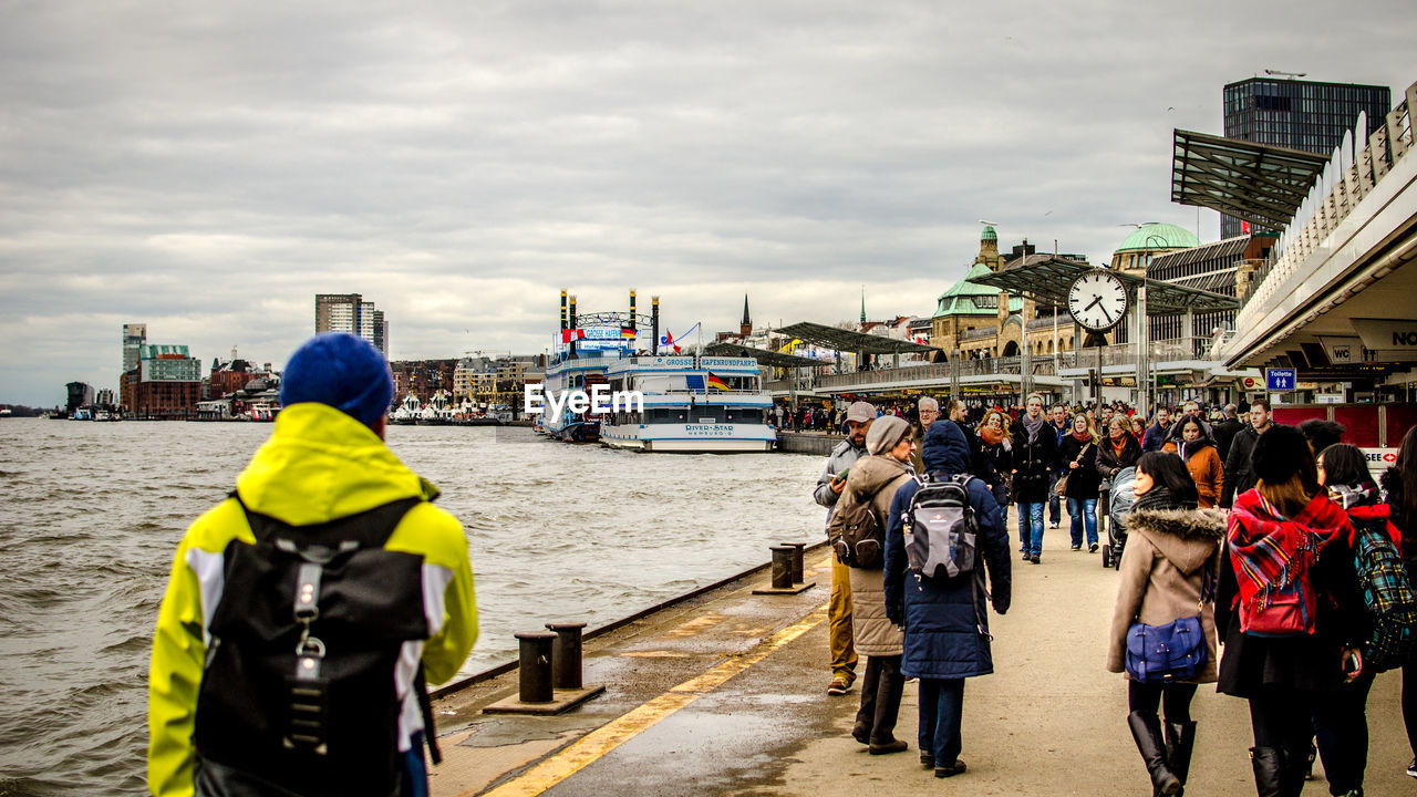 PEOPLE STANDING IN FRONT OF CITY AGAINST SKY