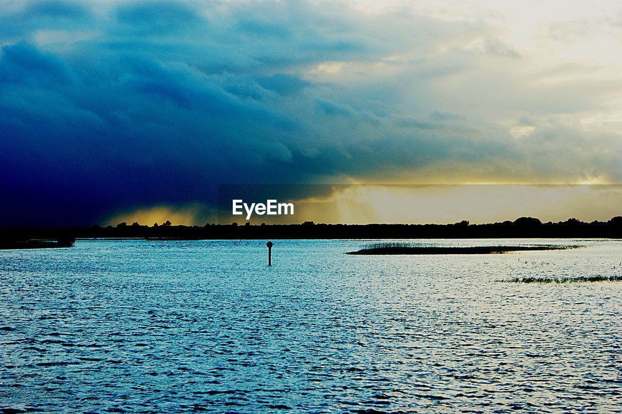 Scenic view of river against cloudy sky