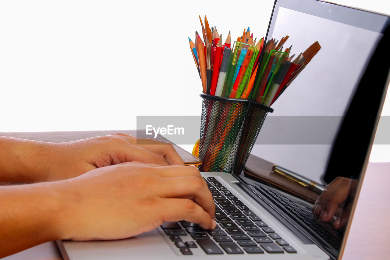 Close-up of person using laptop on table over white background