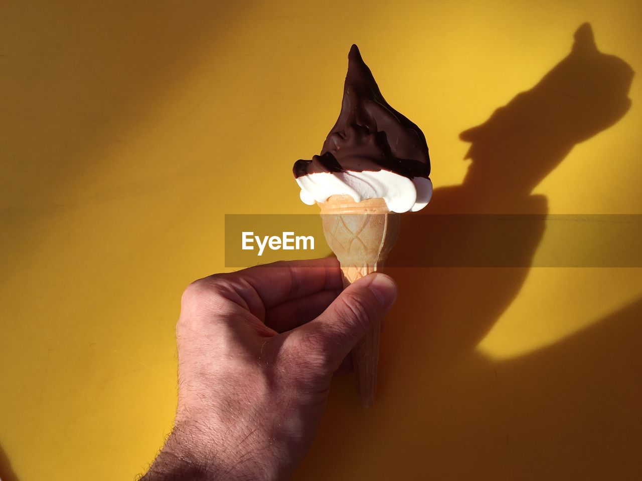 Midsection of man holding ice cream against wall