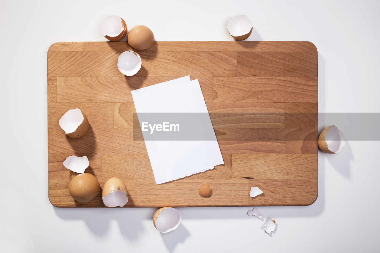 Directly above shot of paper and broken eggshells on cutting board
