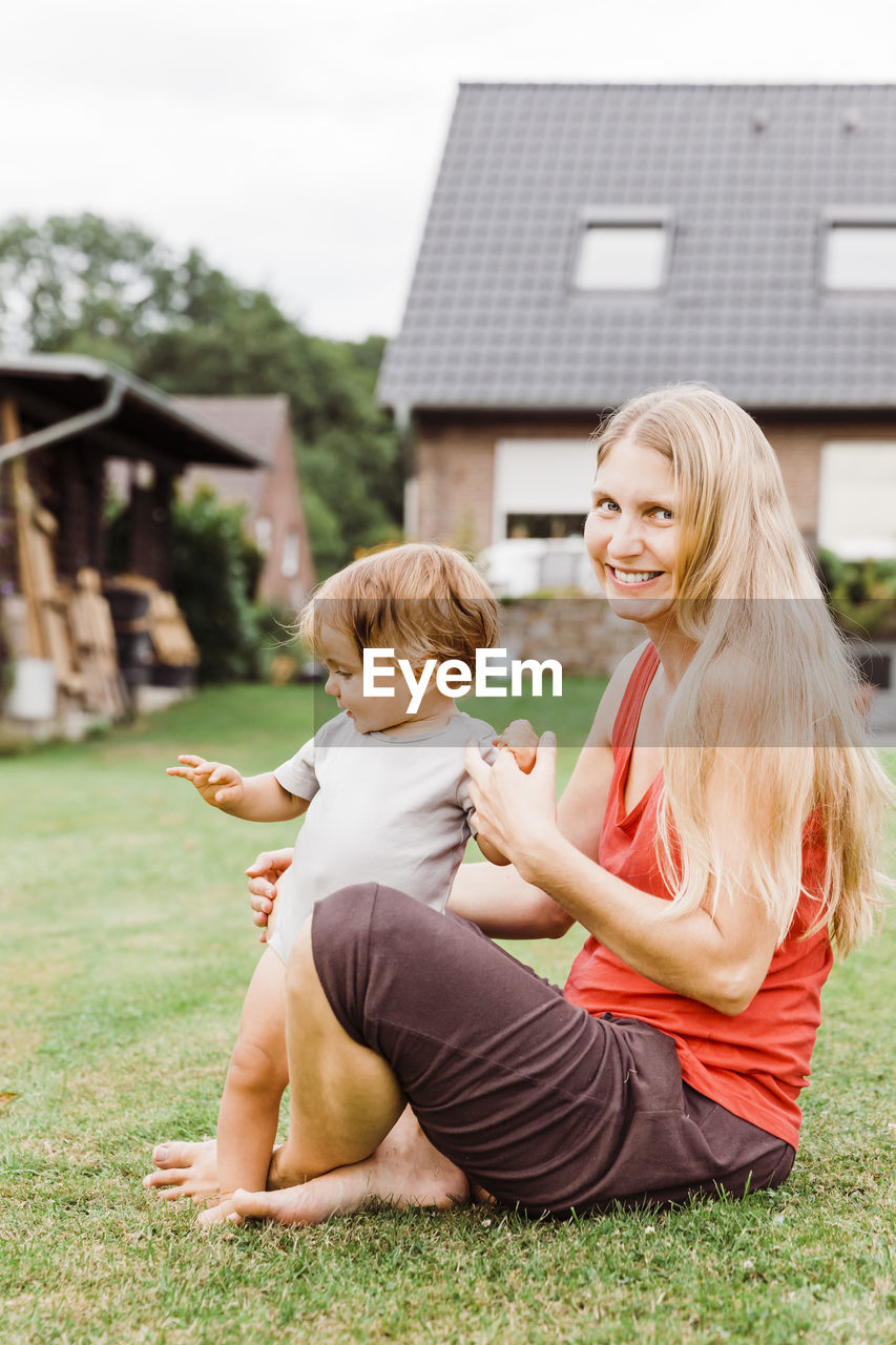 Portrait of woman with baby girl sitting in yard