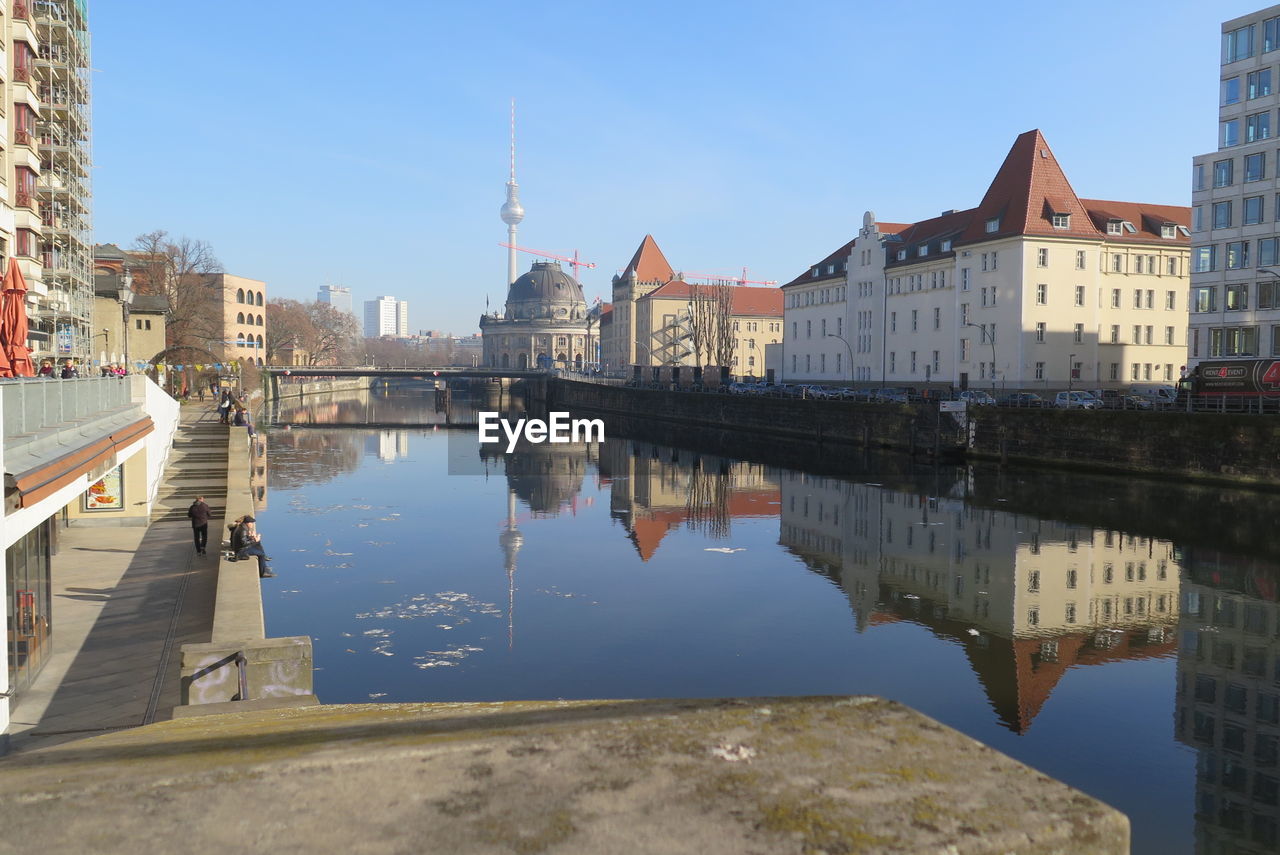 REFLECTION OF CITY ON WATER AGAINST CLEAR SKY