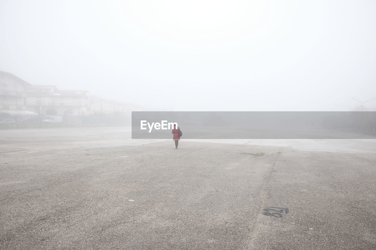 Woman standing at beach during foggy weather
