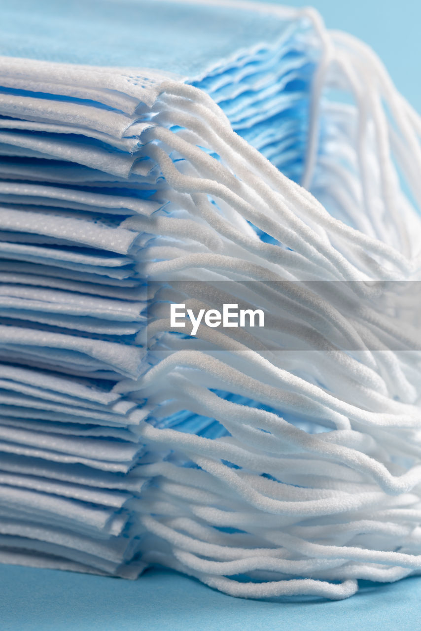 Close-up on a pile of medical face masks on a blue table. coronavirus protective mask supplies.