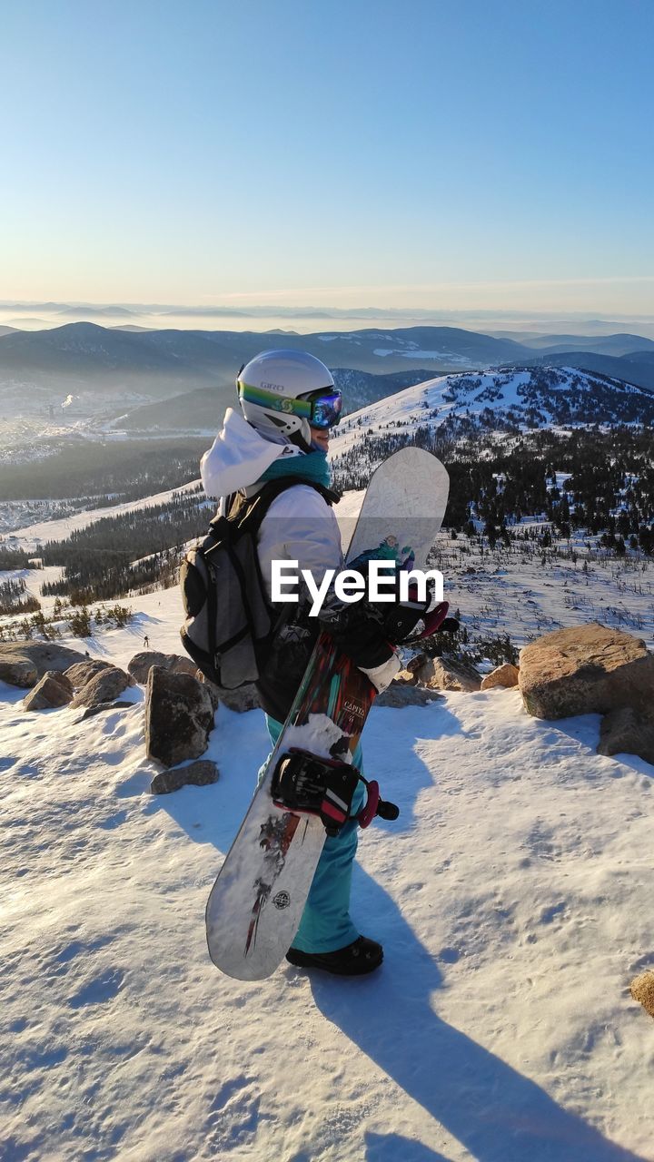 Man carrying snowboard while standing outdoors