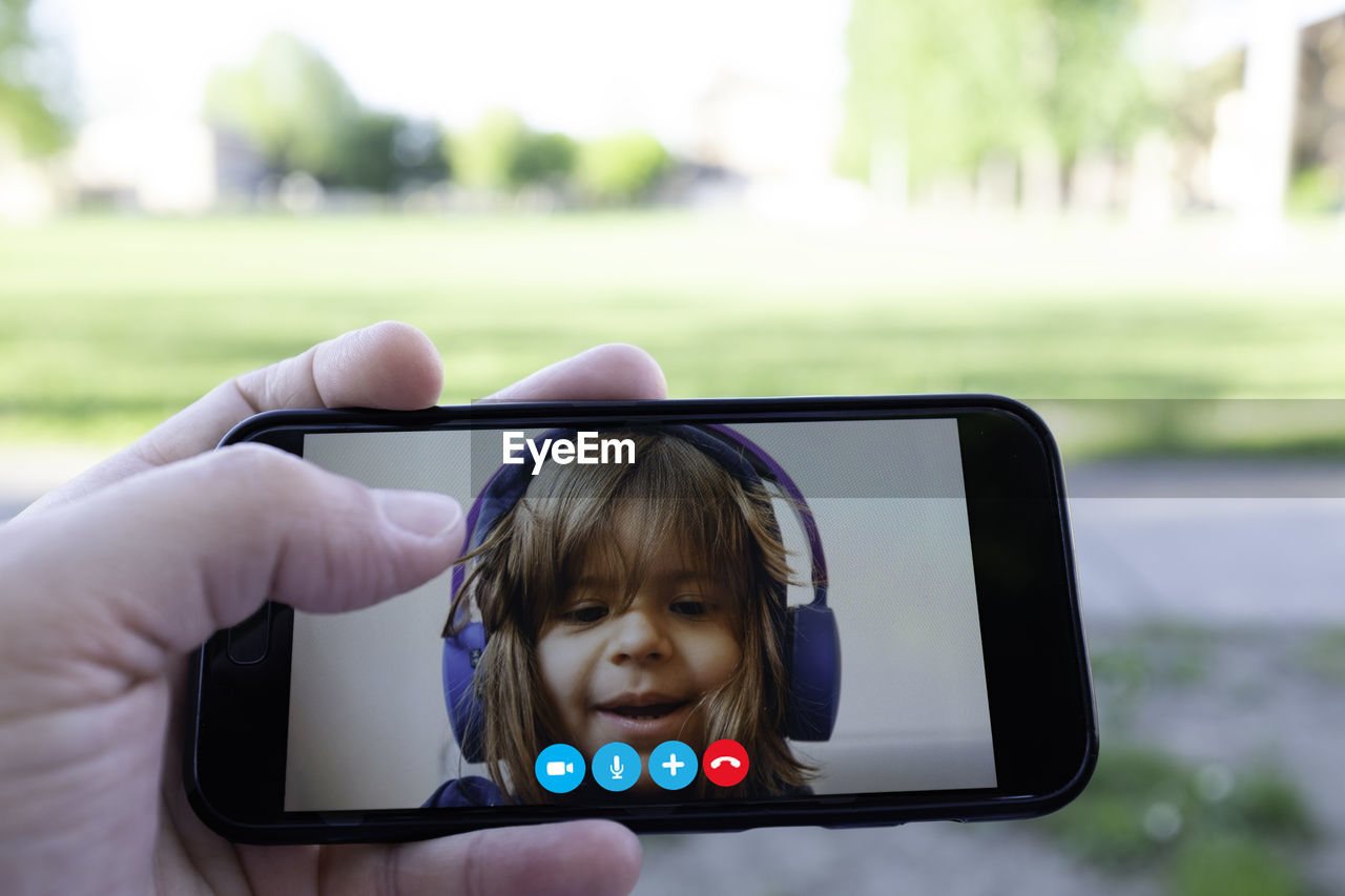 Cropped hand of person video calling with girl over smart phone