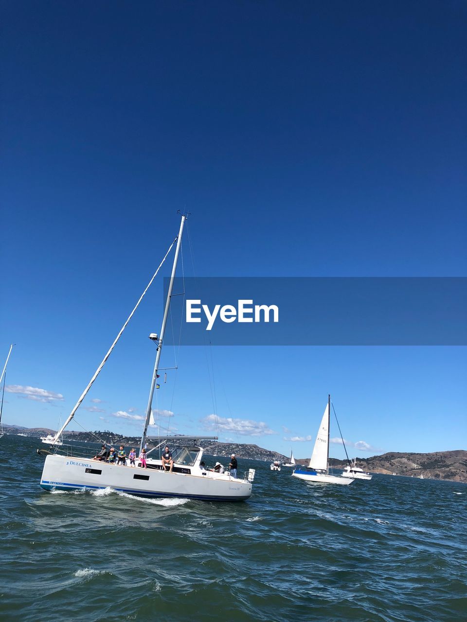 Sailboats sailing in sea against clear blue sky