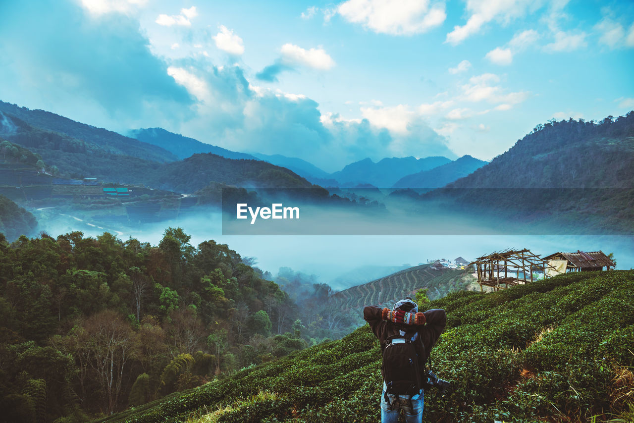 Rear view of man standing on mountain against sky