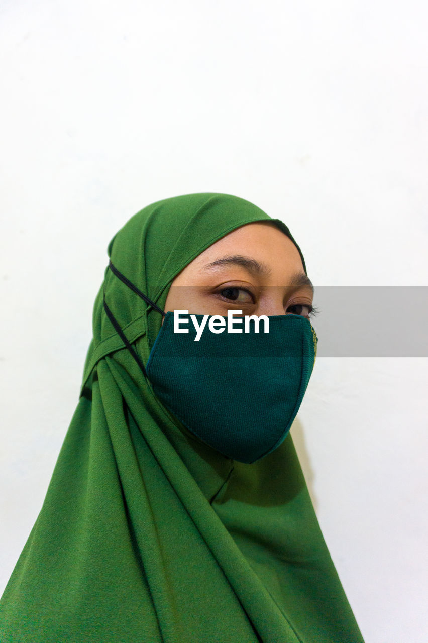 Portrait of young woman covering face over white background