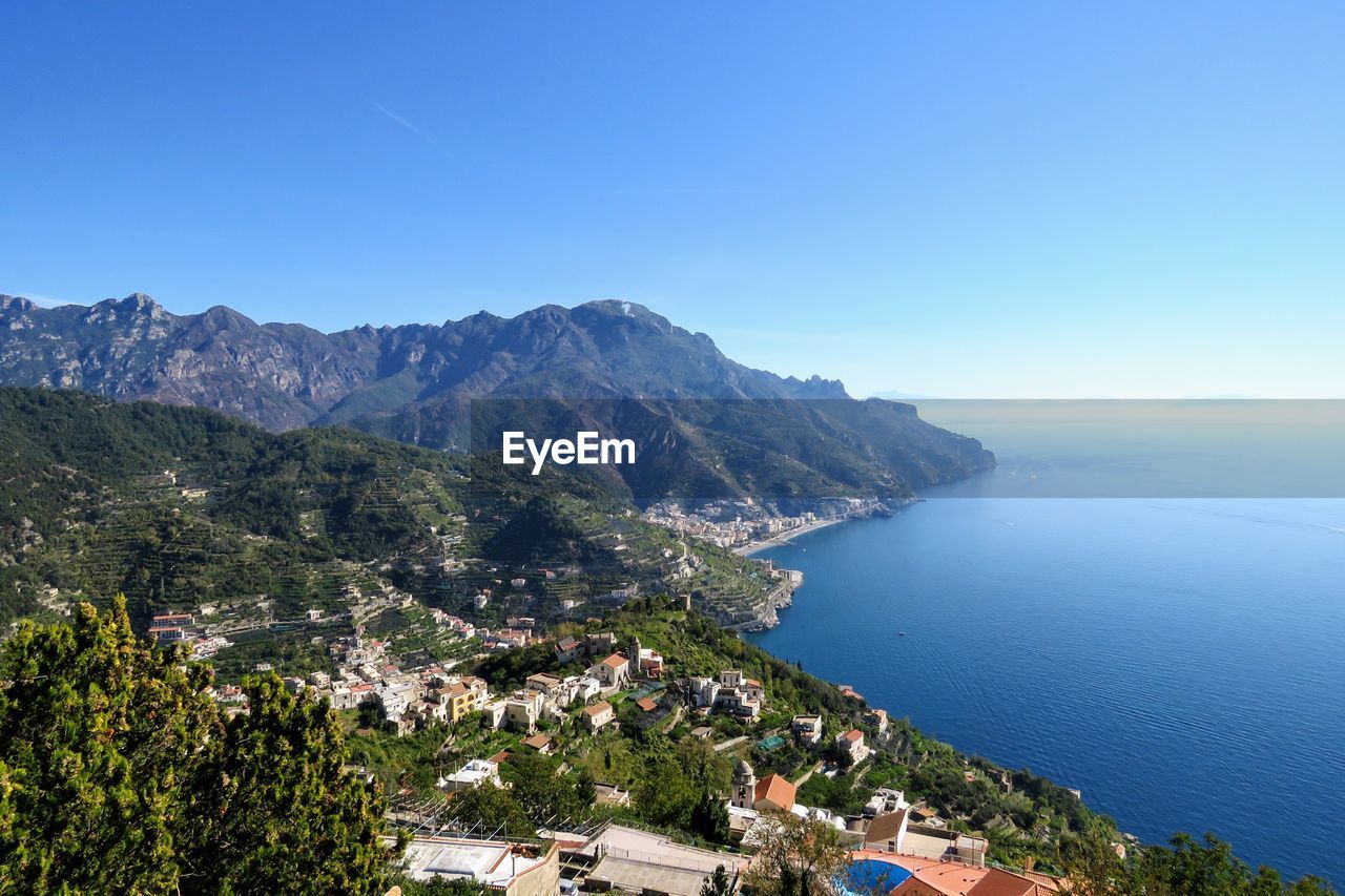 High angle view of sea and mountains against clear blue sky