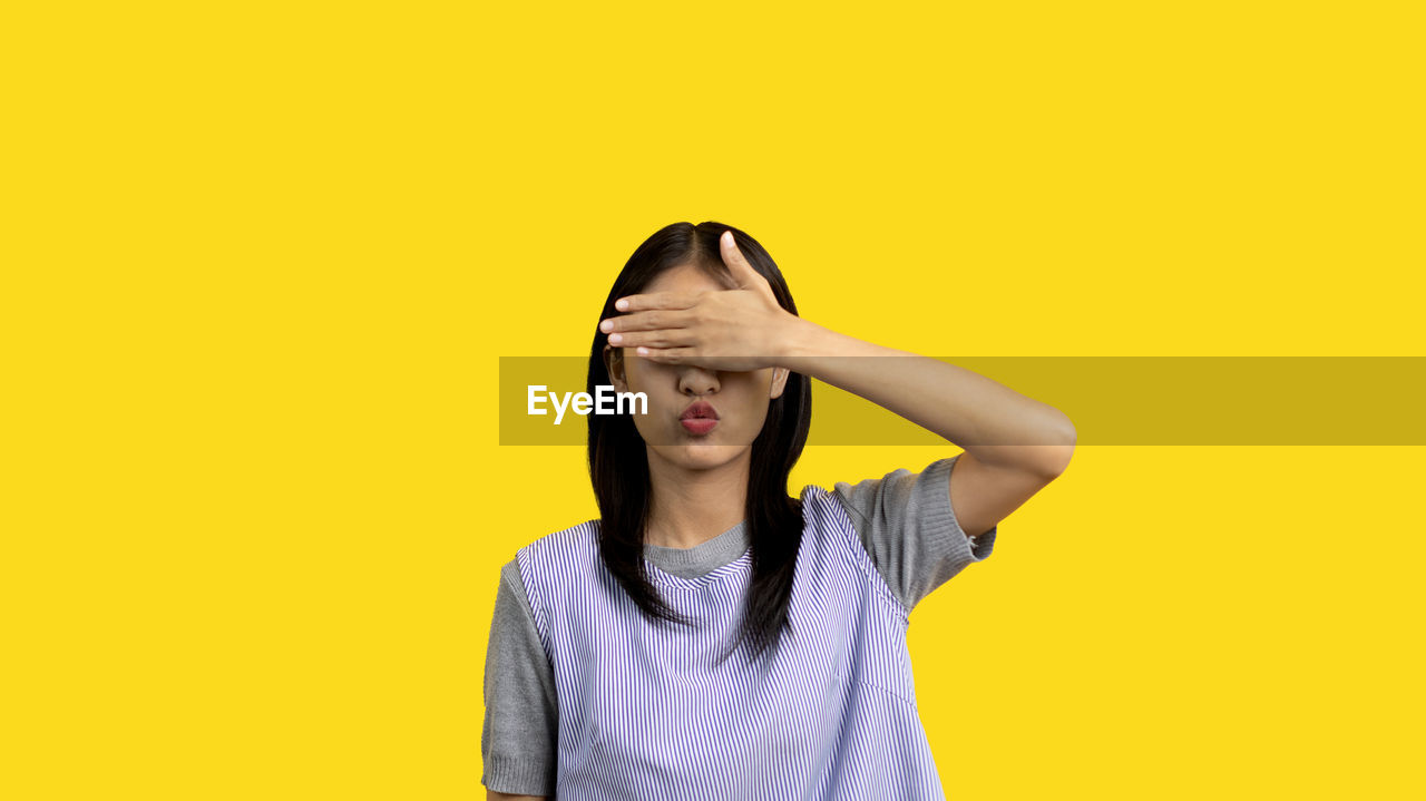 yellow, one person, studio shot, colored background, yellow background, young adult, copy space, portrait, indoors, adult, front view, waist up, women, casual clothing, emotion, clothing, eyes closed, standing, hairstyle, hand, looking, negative emotion, human face, person, headshot, cut out, sadness, frustration, long hair