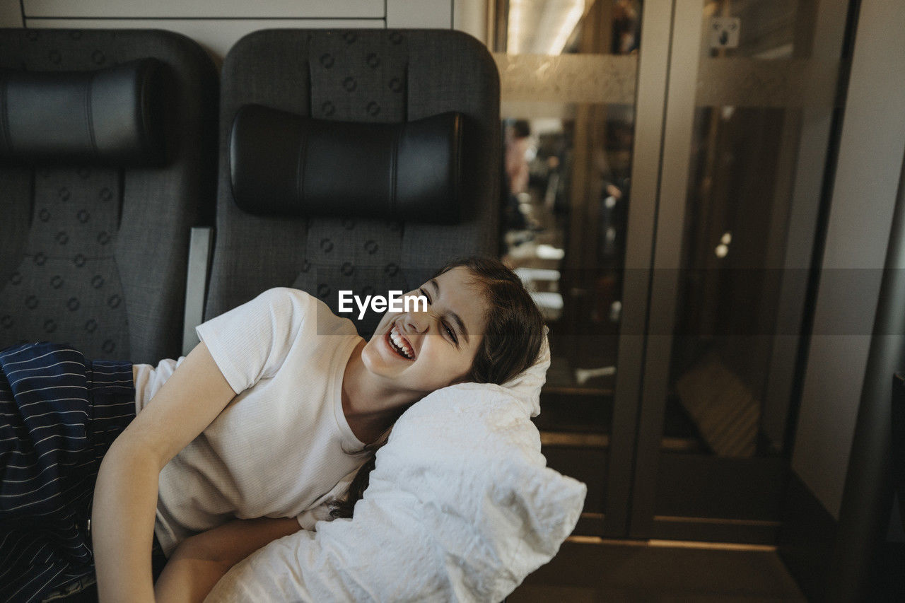 Happy girl laughing while resting on seat in train