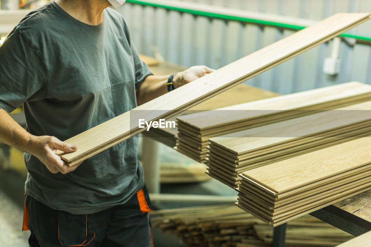 Worker working with planks in wood processing factory