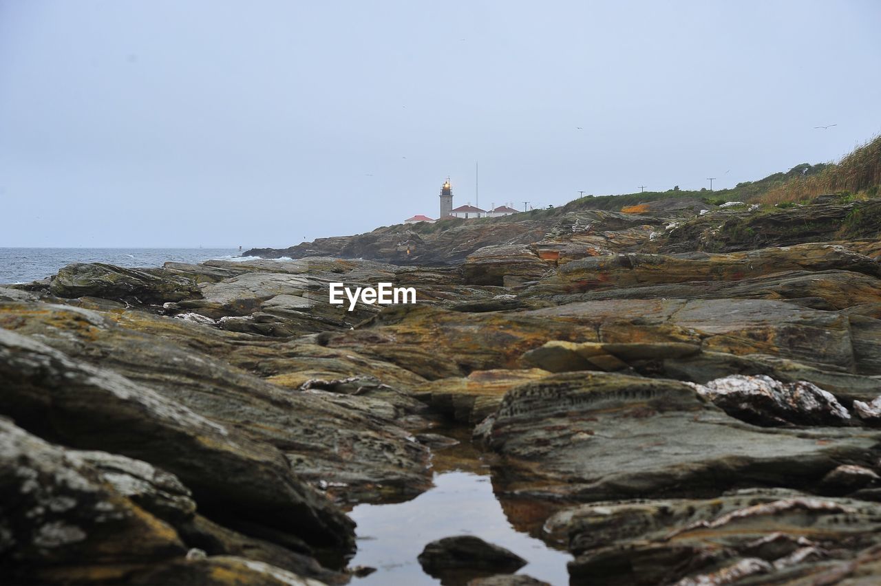 Rocks by sea against clear sky