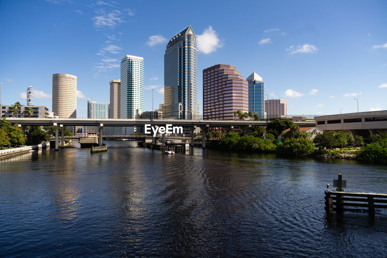 Bridge over river by buildings against sky in city