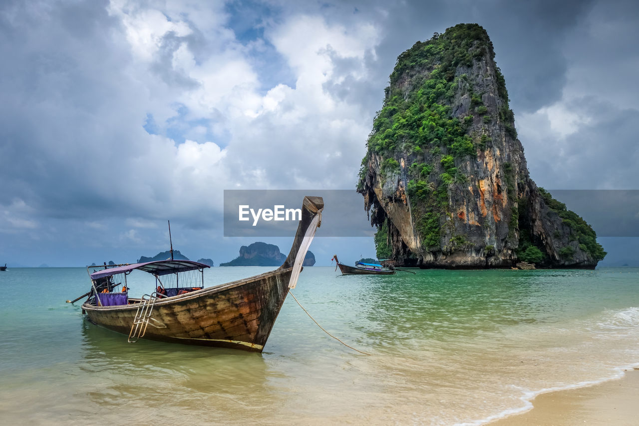 BOAT MOORED ON SHORE AGAINST SKY