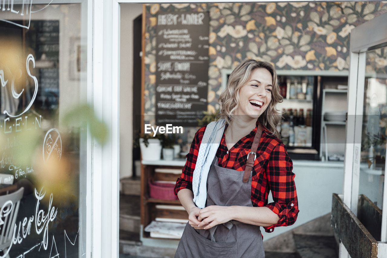 Cheerful businesswoman standing at cafe entrance