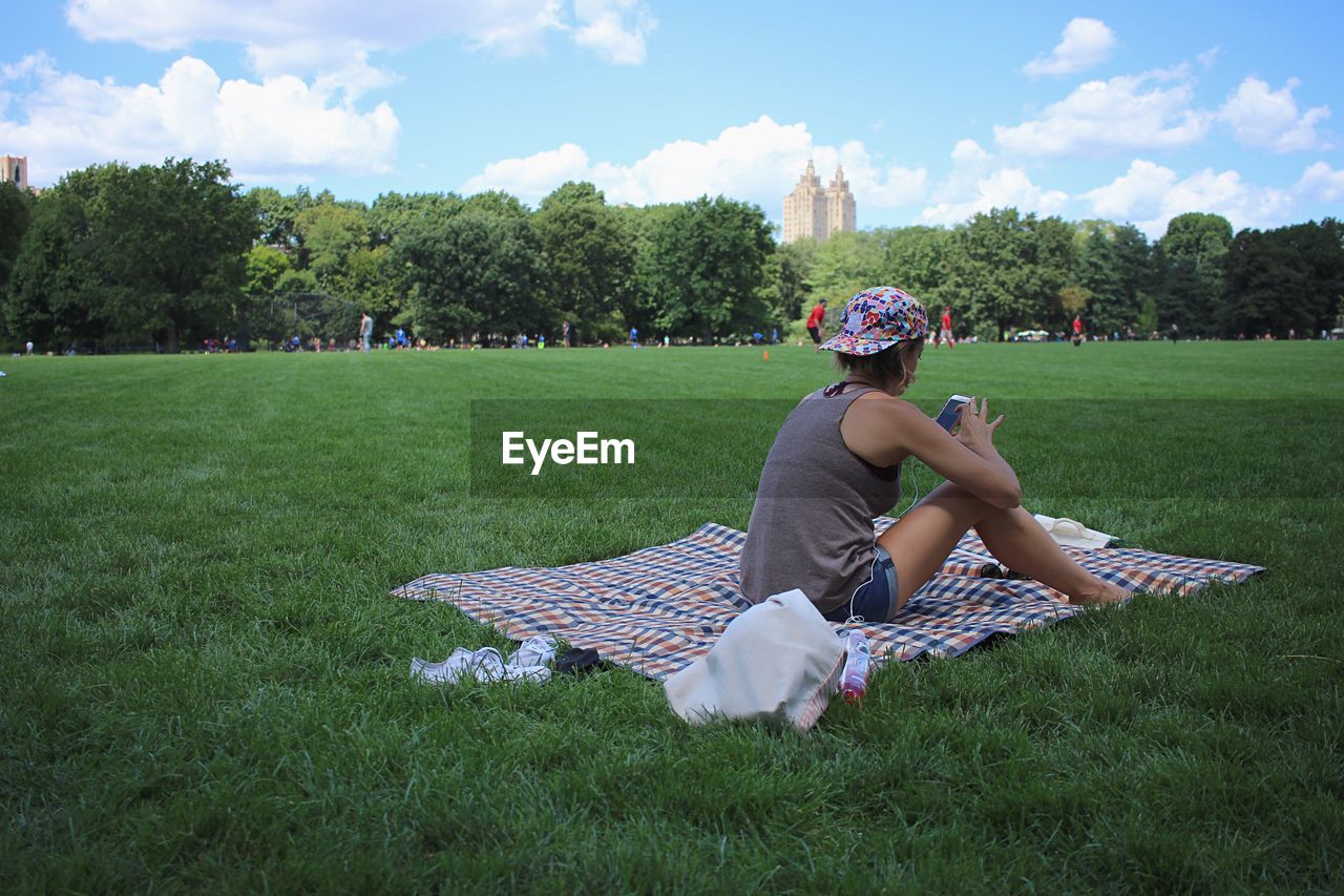 REAR VIEW OF GIRL RELAXING ON GRASSY FIELD