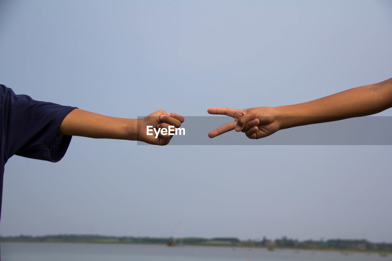 Cropped image of people hands gesturing against clear sky